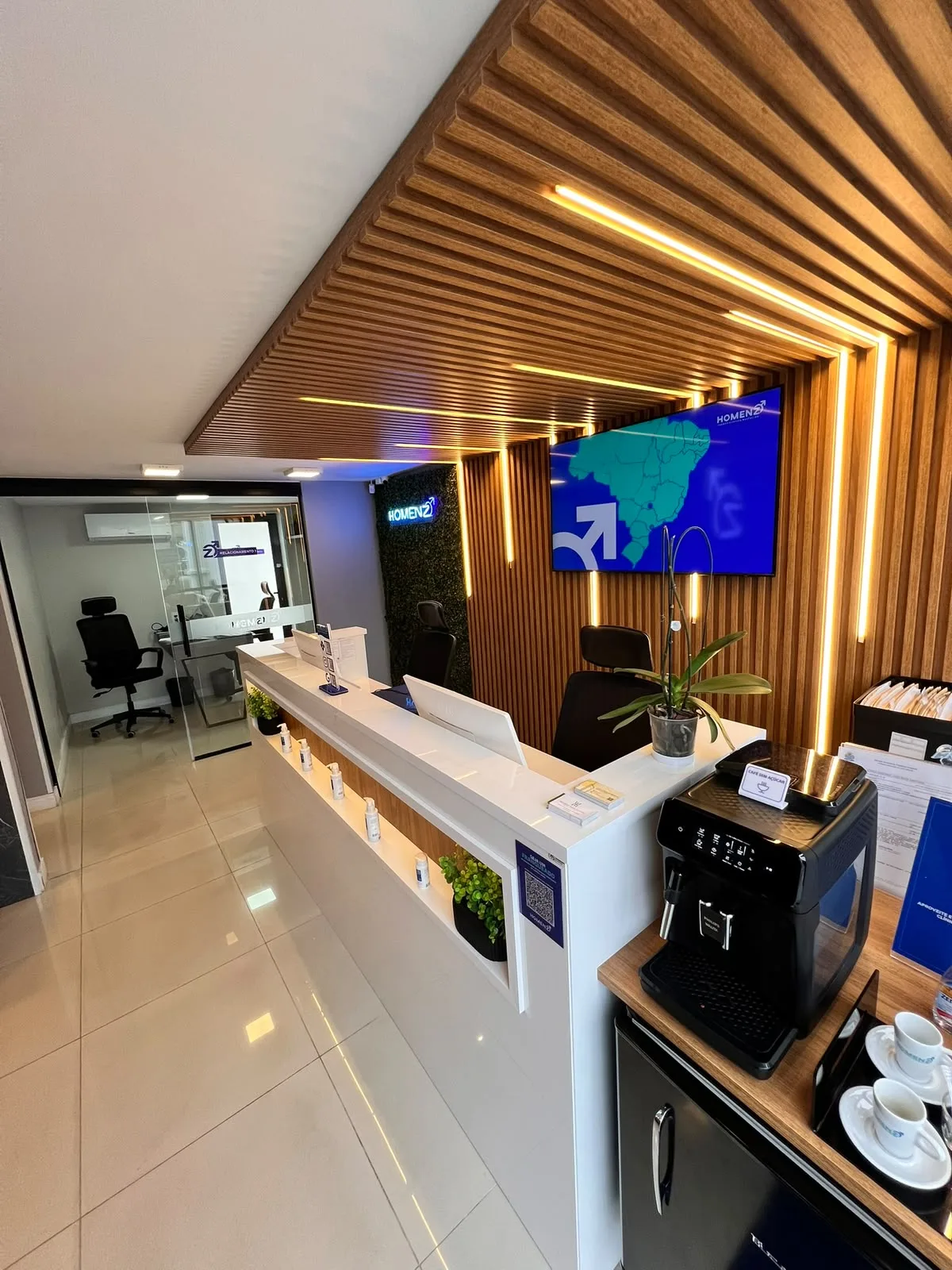 Balcão da recepção da Homenz São Carlos, com cafeteira e televisão